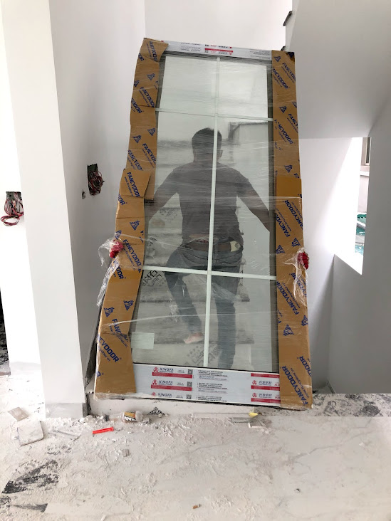 Cửa kính Eurowindow mới bọc carton đang được lắp đặt trong nhà đang xây dựng